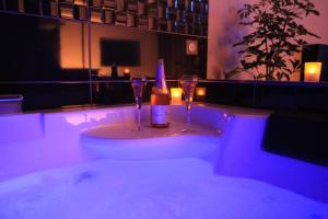 a bath tub with two glasses and a bottle of wine at Le Purple YourHostHelper in Allevard