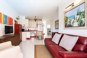 a living room with a red couch and a kitchen at Appartamento fronte mare a Playa de Las Vistas in Arona