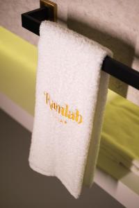 a towel with the word familiar hanging on a rack at Ramlah Resort Qatar in Mesaieed