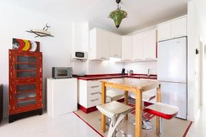 a kitchen with white cabinets and a wooden table at Appartamento fronte mare a Playa de Las Vistas in Arona