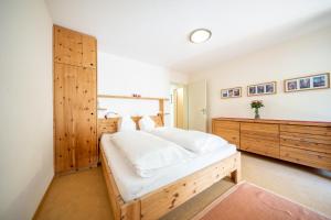 1 dormitorio con 1 cama blanca grande y armario de madera en 2205 Schoen eingerichtete Wohnung mit stilvollem Flair, en Vulpera