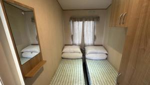 a small room with two beds and a mirror at 27 Rickardos Holiday Lets in Louth