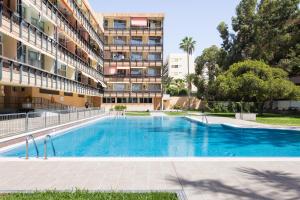 a swimming pool in front of a building at Appartamento fronte mare a Playa de Las Vistas in Arona