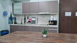 a kitchen with white cabinets and a table with a plant at Regalia Sky pool Hostel @ 969 in Kuala Lumpur