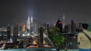 a man looking at a city skyline at night at Regalia Sky pool Hostel @ 969 in Kuala Lumpur