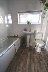 a bathroom with a toilet and a sink and a tub at #1 Limes by DerBnB, Modern 1 Bedroom Apartment, Free Parking, WI-FI & Netflix Near Royal Derby Hospital in Derby