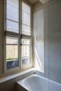 ein Bad mit einer Badewanne und einem Fenster in der Unterkunft Hotel Porte Brunet in Saint-Émilion