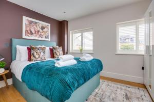 a bedroom with a blue bed with towels on it at Apartment, 2 rooms , up to 5 guests, free pkg -pkg by Tent serviced Apartments in Egham