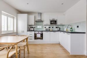 a kitchen with white cabinets and a wooden table at Apartment, 2 rooms , up to 5 guests, free pkg -pkg by Tent serviced Apartments in Egham