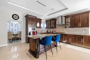uma cozinha com armários de madeira e bancos de bar azuis em Blu Diamond Luxury Estate Home em Nassau