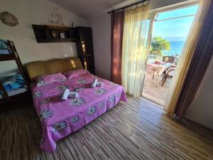 a bedroom with a pink bed and a sliding glass door at Apartments Hanna in Gdinj