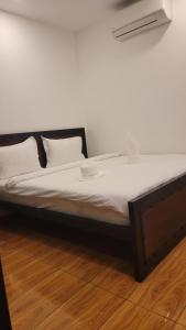 Park Inn Boutique and Hostel في كامبوت: سرير بملاءات ووسائد بيضاء على أرضية خشبية