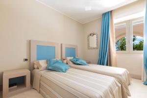 トッレ・ラピッロにあるVilla Bianca by Perle di Pugliaのベッドルーム1室(青い枕のベッド2台付)