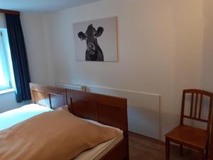 ein Schlafzimmer mit einem Bett und einem Bild einer Kuh an der Wand in der Unterkunft Ferienwohnung Melanie in Obergessertshausen