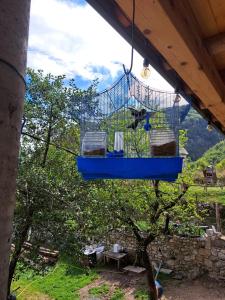 een blauwe vogelkooi hangend aan een dak bij Guesthouse Te Tata in Theth