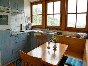 cocina con mesa de madera y cocina con armarios azules en Ferienwohnungen Ringlihof, en Horben