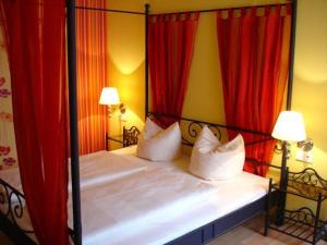 a bed room with a red bedspread and two lamps at Hotel & Pension NOlift in Dresden