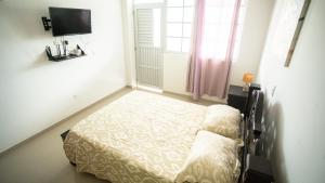 a small bedroom with a bed and a tv at Alojamientos Turísticos Shalain in San Andrés