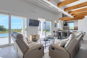 a living room with couches and a table and a kitchen at Villa Civitan with infinity pool in Novigrad in Nova Vas