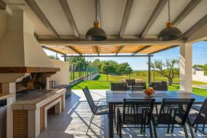 a patio with a table and chairs and a fireplace at Villa Civitan with infinity pool in Novigrad in Nova Vas