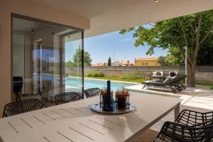 a dining area with a white table and chairs and a pool at Luxury Villa Lipa Tree with pool in Novigrad in Novigrad Istria