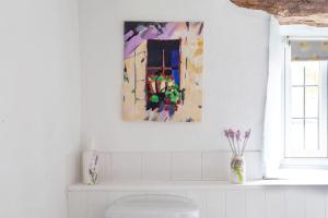Baño con una pintura en la pared sobre un aseo en Cosy Cotswolds cottage with strong WiFi and self check in service, en Gloucestershire 52 fotos más