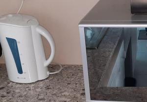 a white tea kettle sitting on a counter next to a microwave at Mount Castleton in Plettenberg Bay