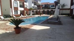 einen Pool mit Stühlen und Sonnenschirmen neben einem Gebäude in der Unterkunft SEVEN SHADES OF CORAL VILLAGE - suites & pool in a residence close to the beach in Punta Cana