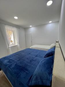 ein Schlafzimmer mit einem blauen Bett und einem Fenster in der Unterkunft Apartmani Edo in Stolac