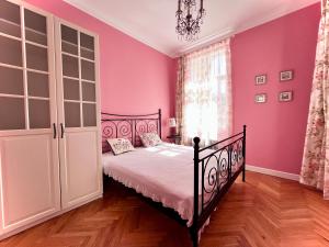 une chambre rose avec un lit et un lustre dans l'établissement Bohemian City - Amazing View, Garage, à Karlovy Vary