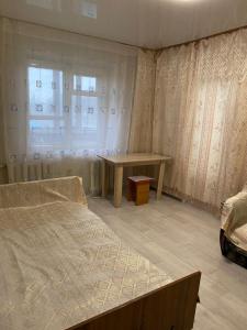 a bedroom with a bed and a table and a window at Гагарина 34 рядом с автовокзалом in Oral