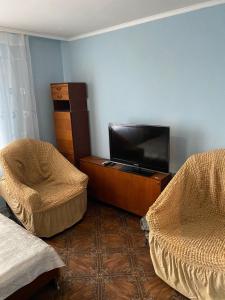 a living room with a flat screen tv and two chairs at Гагарина 34 рядом с автовокзалом in Uralsk