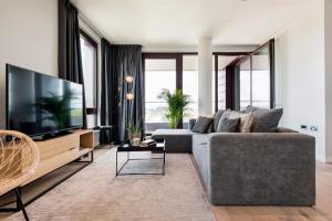 un salon avec un canapé gris et une grande télévision dans l'établissement Gravity Camden Lock Apartments, à Londres