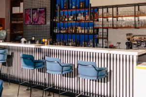 um bar com cadeiras azuis num quarto em Holiday Inn Belgrade, an IHG Hotel em Belgrado