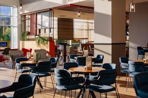 un ristorante con sedie blu, tavoli e finestre di Holiday Inn Belgrade, an IHG Hotel a Belgrado