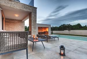 un patio con una mesa y una piscina en Modern villa Omnia with pool and grill in Pula en Loborika