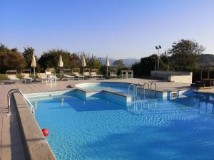 a large swimming pool with blue water and chairs at Coldimolino Resort in Gubbio