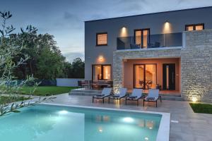 a house with a swimming pool in front of it at Modern villa Omnia with pool and grill in Pula in Loborika
