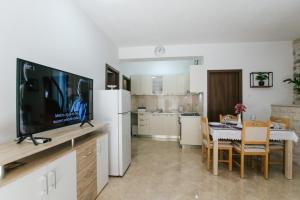 ein Wohnzimmer mit einem TV und eine Küche mit einem Tisch in der Unterkunft Apartment Dajana near the beach in Kaštela