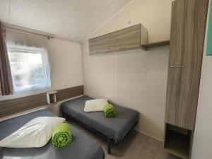 サンギネにあるMobilandes Sanguinetのベッド2台と窓が備わる小さな客室です。