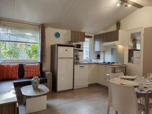 a kitchen and living room with a table and a refrigerator at Mobilandes Sanguinet in Sanguinet