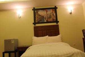 1 dormitorio con 1 cama y una foto en la pared en أجنحة النرجس أبها, en Abha