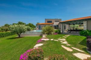 a house with a garden and a yard with flowers at Modern villa Lukas with pool in Vizinada in Vranje Selo