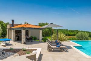 a patio with chairs and an umbrella next to a pool at Modern villa Lukas with pool in Vizinada in Vranje Selo