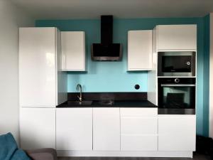 a kitchen with white cabinets and a black microwave at LE PUNTA CANA in Villeurbanne +7 photos