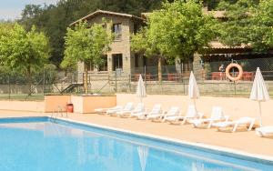a swimming pool with lounge chairs and umbrellas at CAMPING SÈNIA RUPIT in Rupit