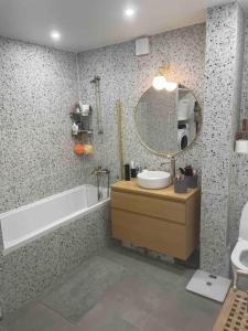 ein Badezimmer mit einer Badewanne, einem Waschbecken und einem Spiegel in der Unterkunft Superbe 4 pièces in Vanves