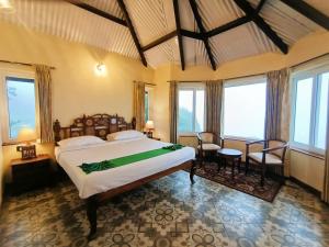 a bedroom with a large bed in a room with windows at Teanest Nightingale by Nature Resorts in Kotagiri