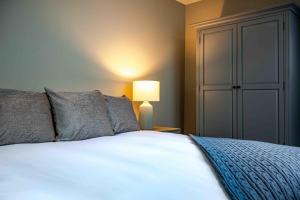 um quarto com uma cama branca e um candeeiro em Bonnie Lodge by Broadford Hotel em Broadford