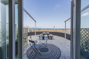 een balkon met een tafel en stoelen en het strand bij Haya Seaview - 'The Casino' in Scheveningen